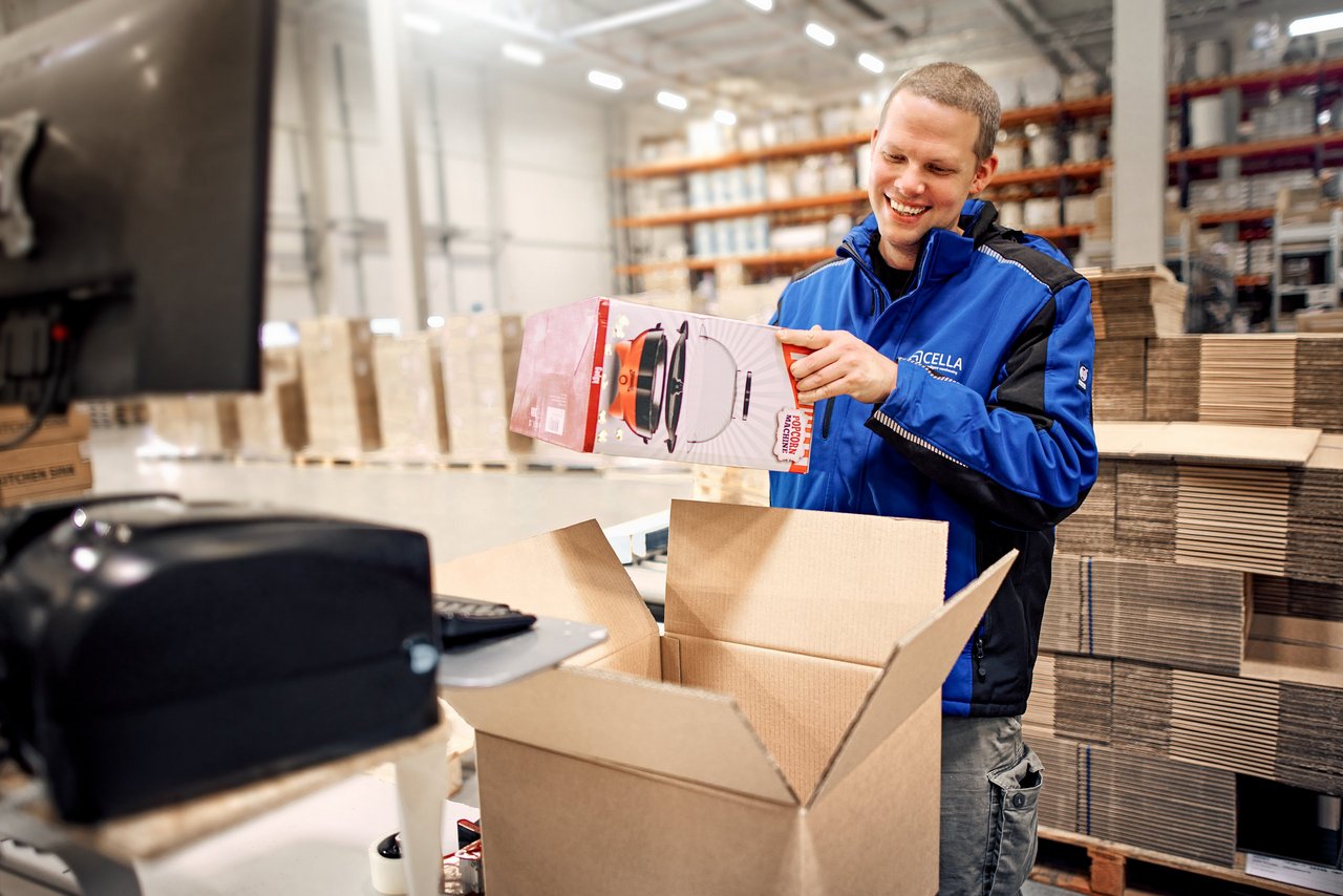 Cella Mitarbeiter verpackt Produkt im Lager für Versand über eBay, Etsy oder Otto
