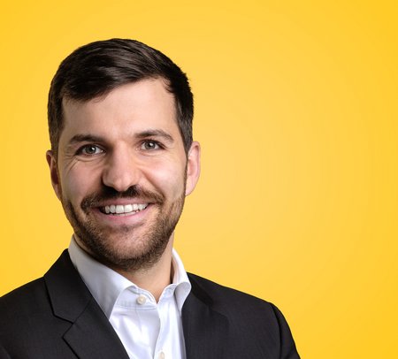 Portrait von Nick Helleberg, COO der Greenforce Future Food AG, im Business-Outfit vor gelbem Hintergrund