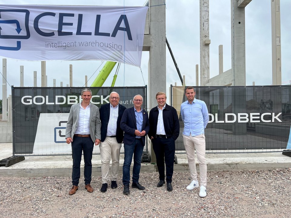 Fünf Männer beim Stützenfest vor dem Rohbau der neuen Logistikhalle von Cella in Altenberge.