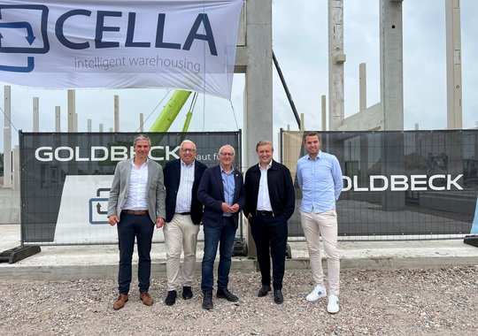 Fünf Männer beim Stützenfest vor dem Rohbau der neuen Logistikhalle von Cella in Altenberge.